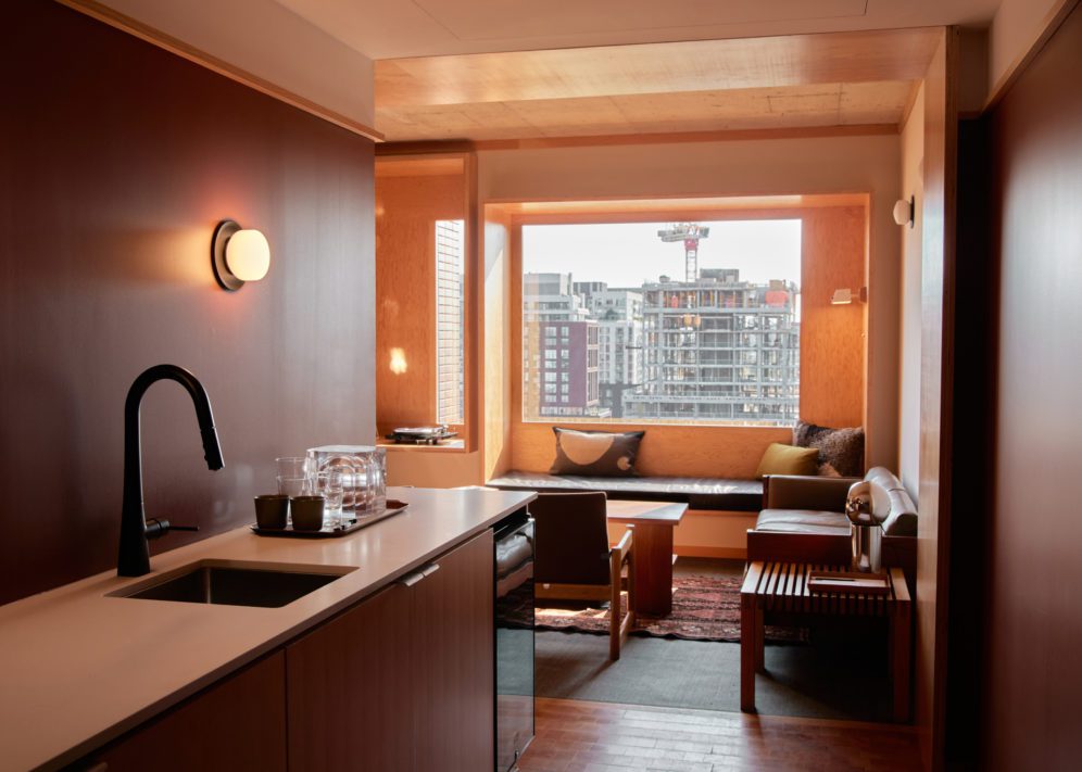 A sink with dishwasher opens up to a large living room with windows and natural light
